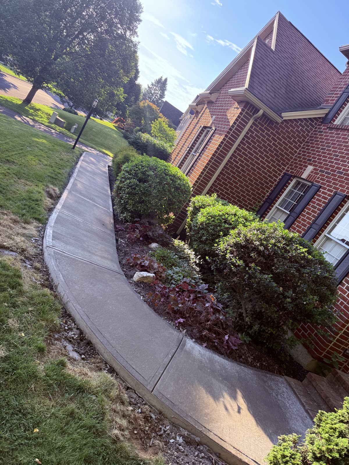 Curved concrete sidewalk poured along a brick home