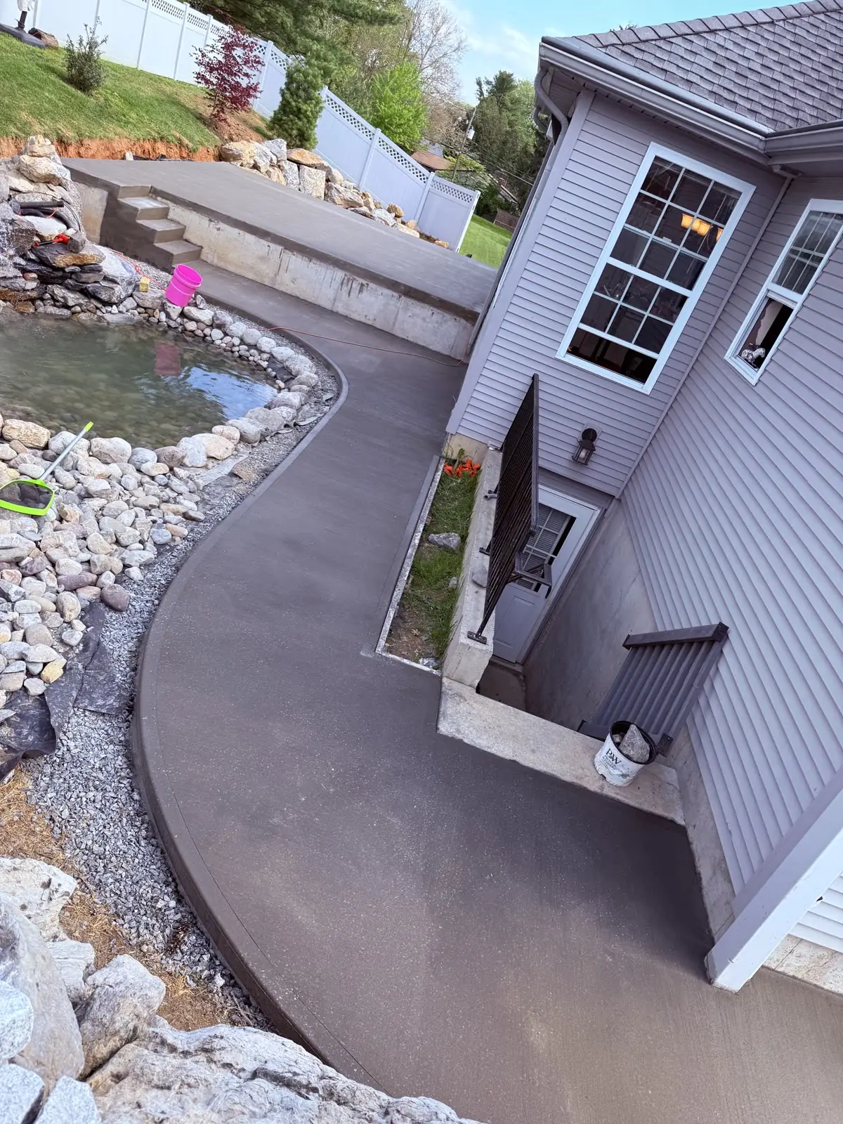 Finished curved concrete walkway poured around a backyard pond