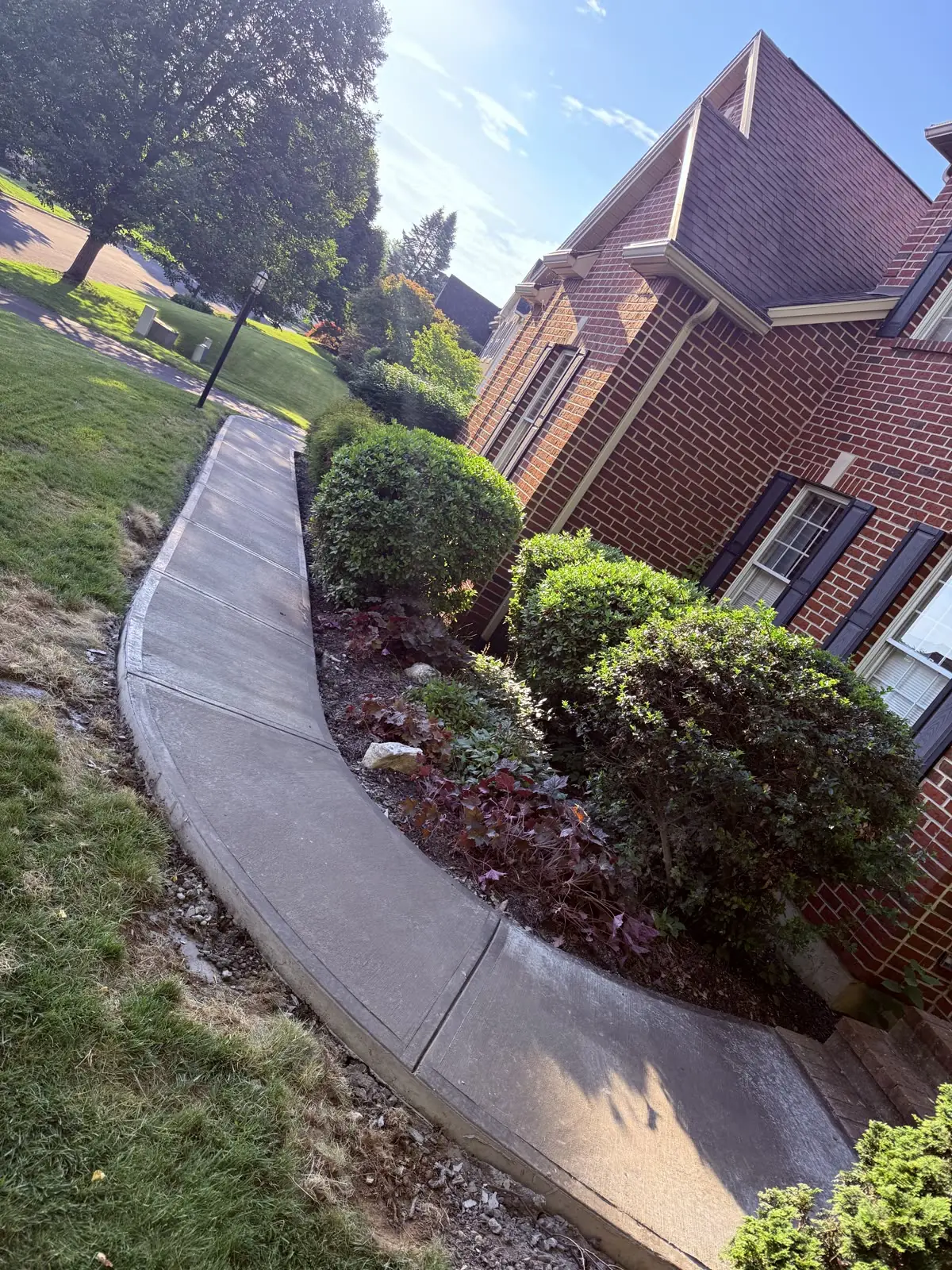 Curved concrete sidewalk poured along a brick home